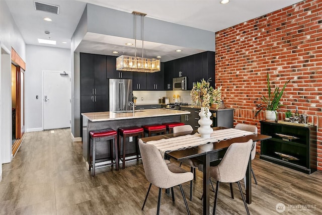 17 W Mercer St Unit 302, Seattle, WA 98119 - dining room with wood finished floors, a chandelier, brick wall, recessed lighting, and baseboards
