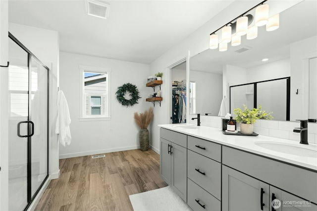 17314 SE 254th Pl, Covington, WA 98042 - full bathroom featuring wood finished floors, double vanity, a stall shower, a walk in closet, and baseboards