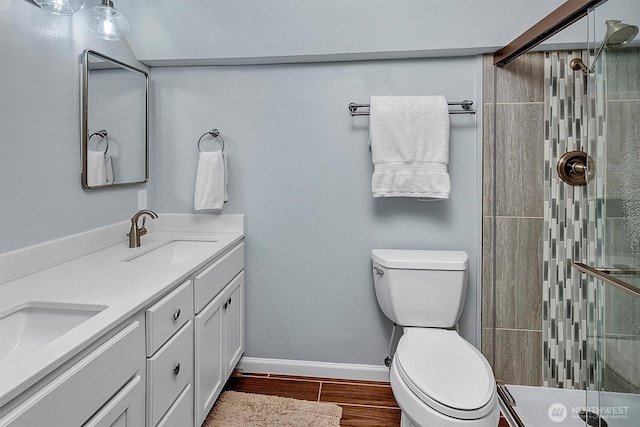 23304 21st Ave SE, Bothell, WA 98021 - bathroom featuring wood finished floors, double vanity, tiled shower, toilet, and baseboards
