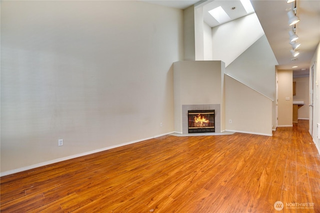 10513 SE 250th Pl Unit F-106, Kent, WA 98031 - unfurnished living room with a skylight, light wood-type flooring, a tiled fireplace, and rail lighting