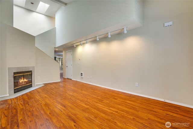 10513 SE 250th Pl Unit F-106, Kent, WA 98031 - unfurnished living room featuring a skylight, rail lighting, wood finished floors, a fireplace, and high vaulted ceiling