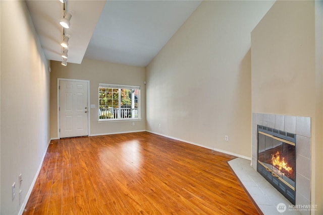 10513 SE 250th Pl Unit F-106, Kent, WA 98031 - unfurnished living room with track lighting, wood finished floors, a tile fireplace, and lofted ceiling