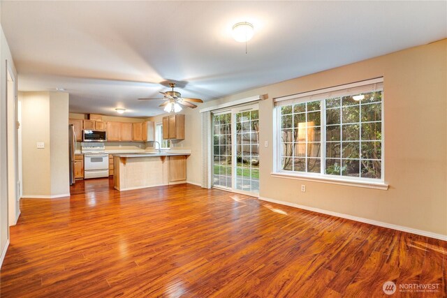 10513 SE 250th Pl Unit F-106, Kent, WA 98031 - kitchen with appliances with stainless steel finishes, a peninsula, open floor plan, dark wood finished floors, and a breakfast bar area