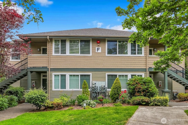 1500 S 18th St Unit F202, Renton, WA 98055 - view of property featuring stairway, a front lawn, and a shingled roof