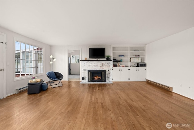 261 SE Adams Ave, Chehalis, WA 98532 - unfurnished living room featuring a baseboard heating unit, a fireplace with flush hearth, plenty of natural light, and light wood finished floors