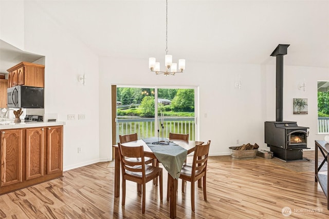 8471 E Caraway Rd, Port Orchard, WA 98366 - dining room featuring light wood-type flooring, healthy amount of natural light, a wood stove, and a chandelier