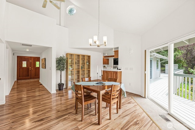 8471 E Caraway Rd, Port Orchard, WA 98366 - dining room featuring healthy amount of natural light, high vaulted ceiling, light wood-type flooring, and a chandelier