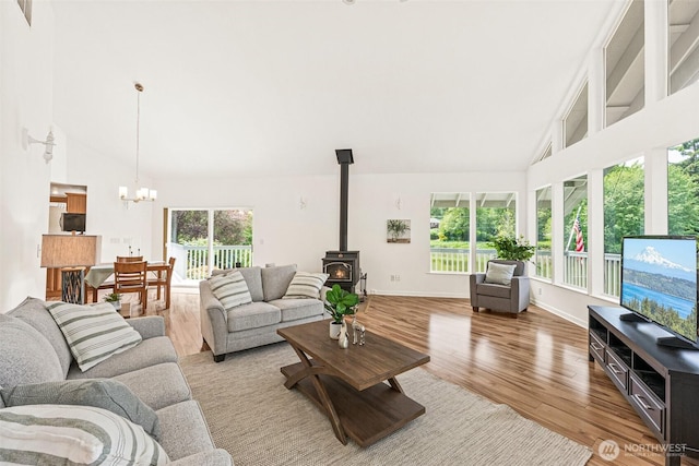8471 E Caraway Rd, Port Orchard, WA 98366 - living area with high vaulted ceiling, wood finished floors, a wood stove, a chandelier, and baseboards
