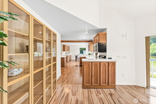 8471 E Caraway Rd, Port Orchard, WA 98366 - kitchen featuring stainless steel microwave, light wood-style floors, brown cabinetry, baseboards, and a peninsula