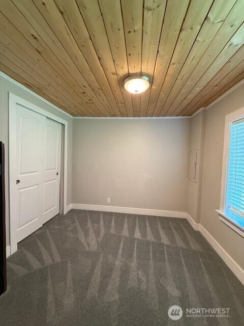14518 Kapowsin Hwy E, Graham, WA 98338 - unfurnished bedroom featuring wood ceiling, dark colored carpet, crown molding, baseboards, and a closet