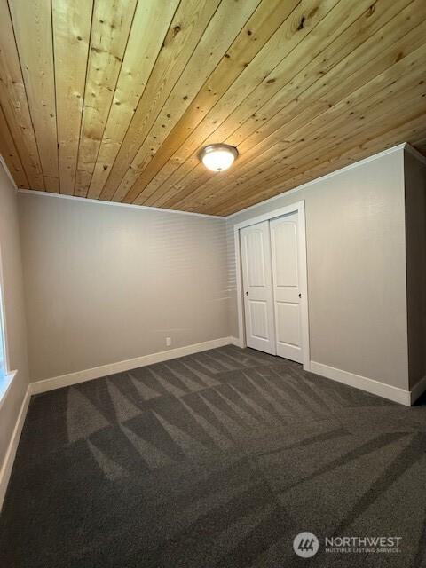 14518 Kapowsin Hwy E, Graham, WA 98338 - spare room featuring wooden ceiling, dark colored carpet, baseboards, and ornamental molding