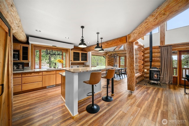 3105 Tamarack Pl, Wenatchee, WA 98801 - kitchen featuring rustic walls, a wood stove, light wood finished floors, a sink, and a kitchen breakfast bar