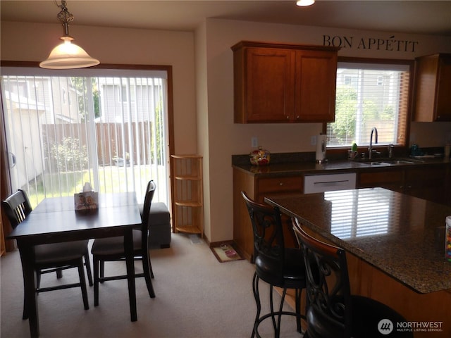 4558 SE Bakken Ct, Port Orchard, WA 98366 - kitchen featuring a sink, brown cabinets, pendant lighting, light colored carpet, and a kitchen breakfast bar