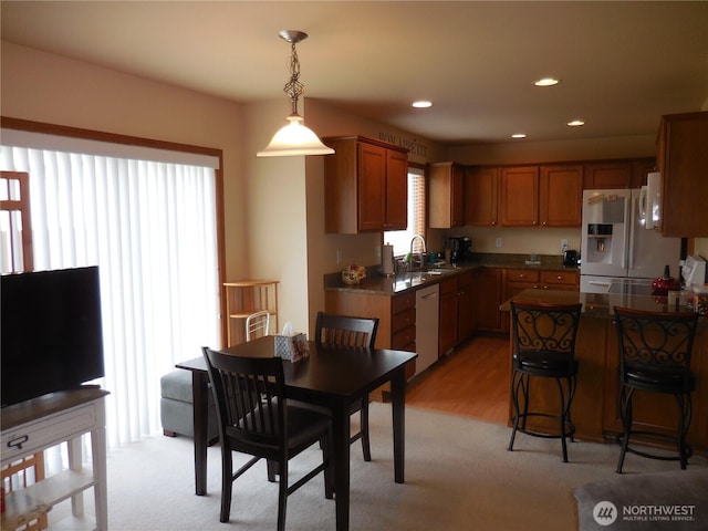 4558 SE Bakken Ct, Port Orchard, WA 98366 - kitchen featuring white refrigerator with ice dispenser, dishwashing machine, dark countertops, decorative light fixtures, and brown cabinets