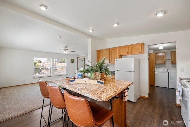 324 Mojave Ct, West Richland, WA 99353 - kitchen featuring white appliances, washer and dryer, a center island, and dark wood-style flooring