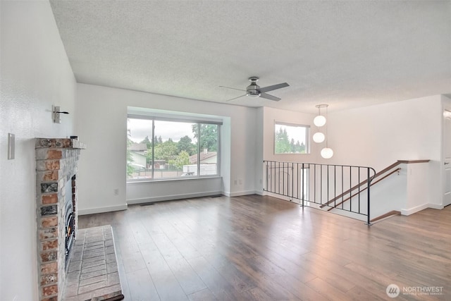 35432 18th Ave SW, Federal Way, WA 98023 - unfurnished living room with a ceiling fan, a textured ceiling, wood finished floors, baseboards, and a fireplace with raised hearth