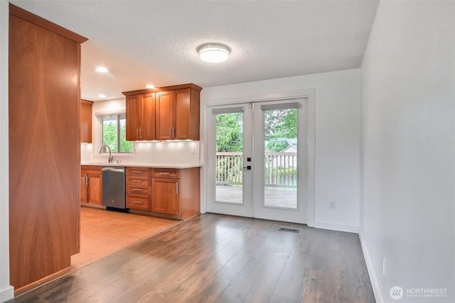 35432 18th Ave SW, Federal Way, WA 98023 - kitchen with stainless steel dishwasher, light countertops, a sink, brown cabinets, and a textured ceiling