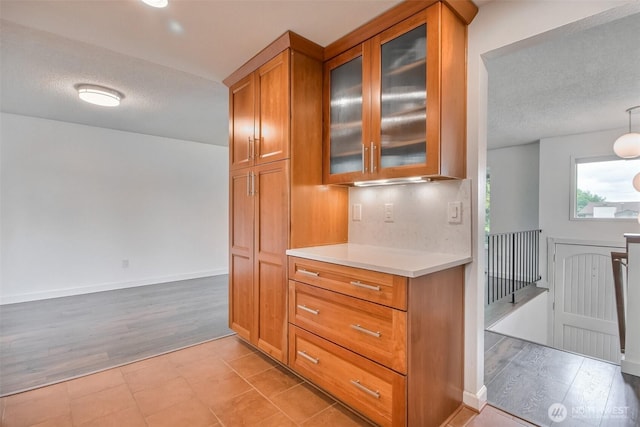 35432 18th Ave SW, Federal Way, WA 98023 - kitchen featuring brown cabinetry, light countertops, a textured ceiling, glass insert cabinets, and light wood finished floors