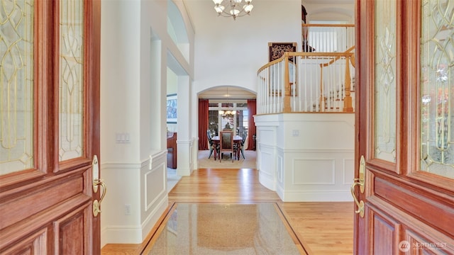 8504 146th Pl SE, Newcastle, WA 98059 - foyer entrance with arched walkways, a chandelier, light wood-style floors, a decorative wall, and a wainscoted wall