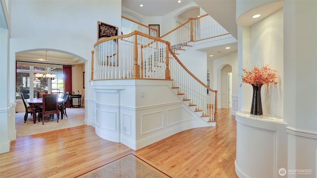 8504 146th Pl SE, Newcastle, WA 98059 - stairs featuring a towering ceiling, a chandelier, wood finished floors, recessed lighting, and arched walkways