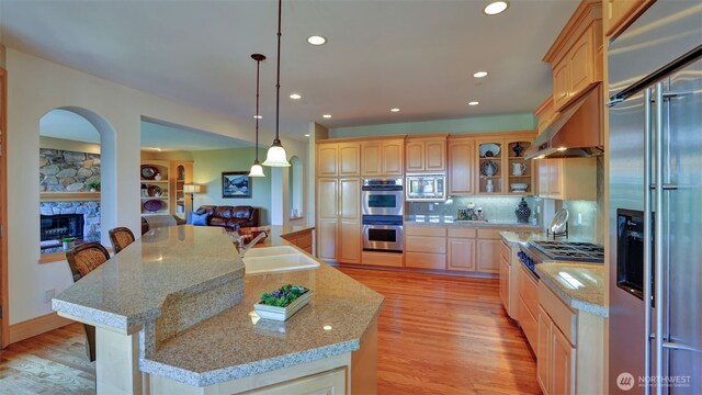 8504 146th Pl SE, Newcastle, WA 98059 - kitchen with built in appliances, a sink, arched walkways, a fireplace, and light brown cabinetry