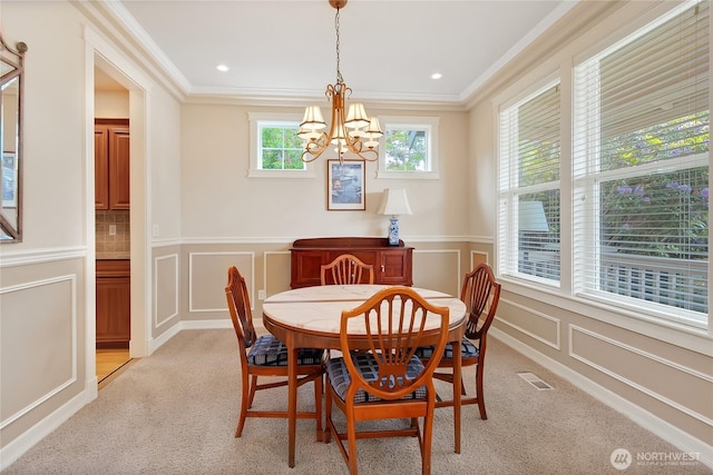 6103 153rd Ave E, Sumner, WA 98390 - dining room featuring a chandelier, ornamental molding, a decorative wall, light colored carpet, and wainscoting