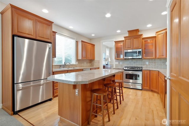 6103 153rd Ave E, Sumner, WA 98390 - kitchen with stainless steel appliances, light wood finished floors, a center island, a kitchen bar, and backsplash