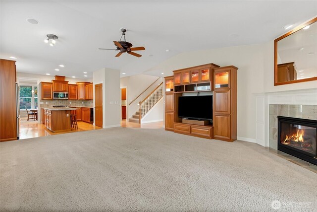 6103 153rd Ave E, Sumner, WA 98390 - unfurnished living room featuring a ceiling fan, lofted ceiling, light colored carpet, a tiled fireplace, and stairway