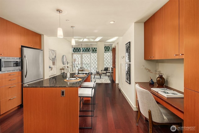 909 5th Ave Unit 303, Seattle, WA 98164 - kitchen featuring appliances with stainless steel finishes, a kitchen island, dark wood-style flooring, and a kitchen breakfast bar