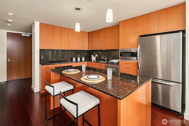 909 5th Ave Unit 303, Seattle, WA 98164 - kitchen with stainless steel appliances, dark wood-type flooring, backsplash, a sink, and a kitchen breakfast bar