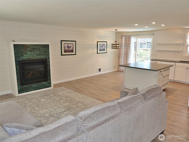 137 S Razor Clam Dr SW, Ocean Shores, WA 98569 - living area with baseboards, light wood-style floors, a glass covered fireplace, recessed lighting, and wooden walls