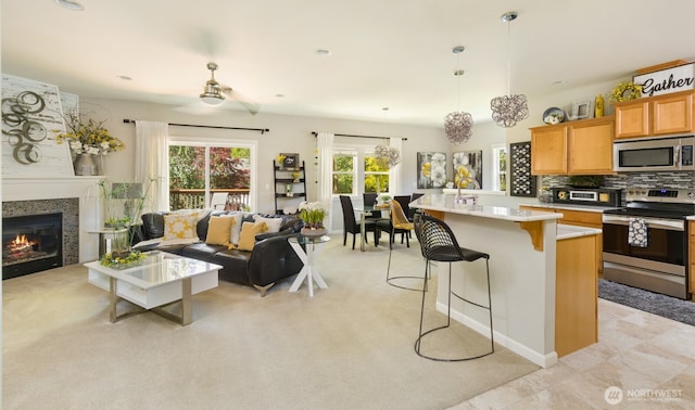 226 Alnus Way, Bremerton, WA 98310 - kitchen featuring appliances with stainless steel finishes, open floor plan, a breakfast bar area, light countertops, and a glass covered fireplace