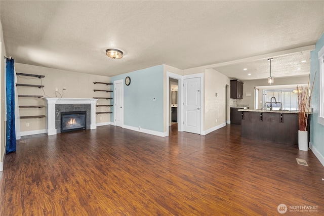 4050 E G St, Tacoma, WA 98404 - unfurnished living room featuring a textured ceiling, a tiled fireplace, and dark wood-style floors
