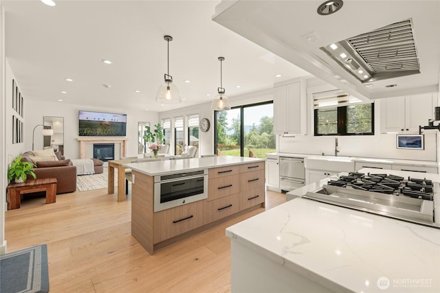 2140 Lagerwey Cir, Lynden, WA 98264 - kitchen with stainless steel appliances, recessed lighting, light wood-style flooring, a glass covered fireplace, and white cabinets