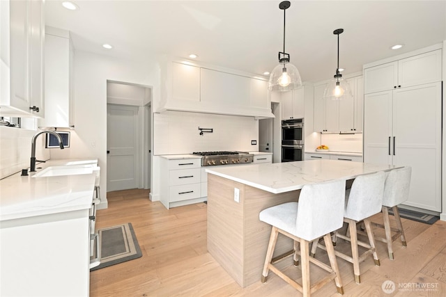 2140 Lagerwey Cir, Lynden, WA 98264 - kitchen with backsplash, appliances with stainless steel finishes, light wood-style floors, a breakfast bar area, and recessed lighting