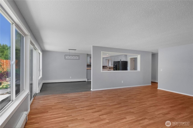9341 Littlerock Rd SW, Olympia, WA 98512 - unfurnished living room with a textured ceiling, light wood-style flooring, a baseboard heating unit, and baseboards