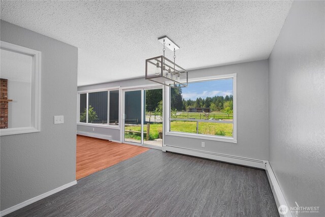 9341 Littlerock Rd SW, Olympia, WA 98512 - unfurnished dining area with a chandelier, wood finished floors, a baseboard heating unit, a textured ceiling, and baseboards