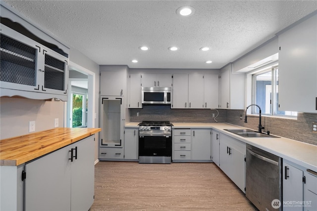 9341 Littlerock Rd SW, Olympia, WA 98512 - kitchen featuring appliances with stainless steel finishes, a sink, a textured ceiling, light wood finished floors, and decorative backsplash