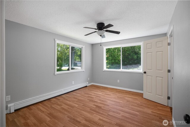 9341 Littlerock Rd SW, Olympia, WA 98512 - unfurnished bedroom featuring a baseboard radiator, a textured ceiling, wood finished floors, baseboards, and a ceiling fan