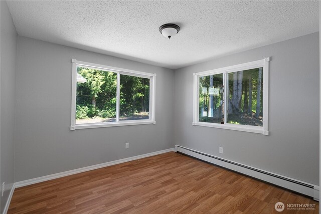 9341 Littlerock Rd SW, Olympia, WA 98512 - empty room featuring baseboard heating, wood finished floors, a textured ceiling, and baseboards