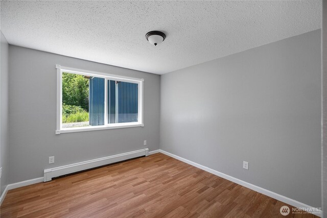 9341 Littlerock Rd SW, Olympia, WA 98512 - unfurnished room featuring a baseboard heating unit, wood finished floors, a textured ceiling, and baseboards