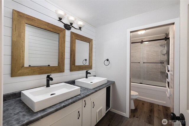 9341 Littlerock Rd SW, Olympia, WA 98512 - bathroom with double vanity, toilet, wood finished floors, and bath / shower combo with glass door