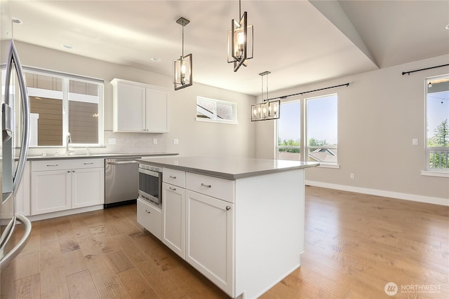 711 Blackstone Ln, Bellingham, WA 98226 - kitchen with stainless steel appliances, light wood-style floors, a kitchen island, white cabinets, and pendant lighting
