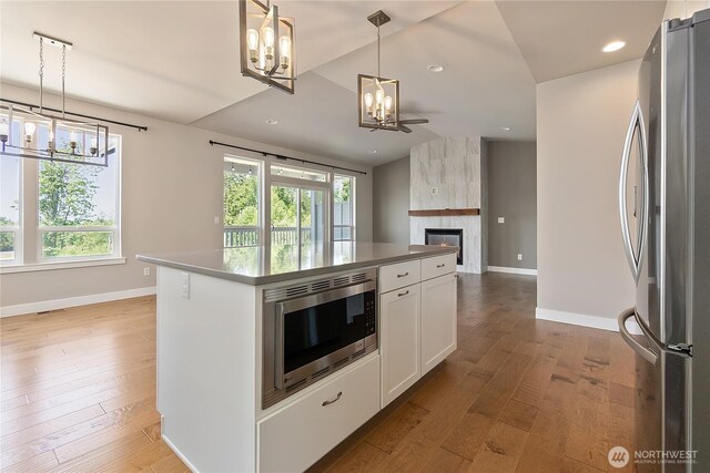 711 Blackstone Ln, Bellingham, WA 98226 - kitchen with stainless steel appliances, a chandelier, baseboards, white cabinets, and wood finished floors