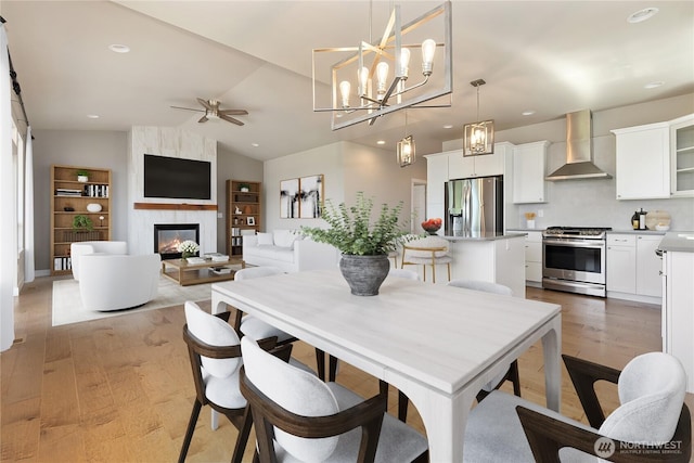 711 Blackstone Ln, Bellingham, WA 98226 - dining room with ceiling fan, light wood-style flooring, a large fireplace, vaulted ceiling, and recessed lighting