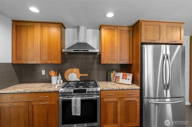 1484 SW Snively Ave, Chehalis, WA 98532 - kitchen with appliances with stainless steel finishes, wall chimney exhaust hood, brown cabinetry, decorative backsplash, and light stone countertops
