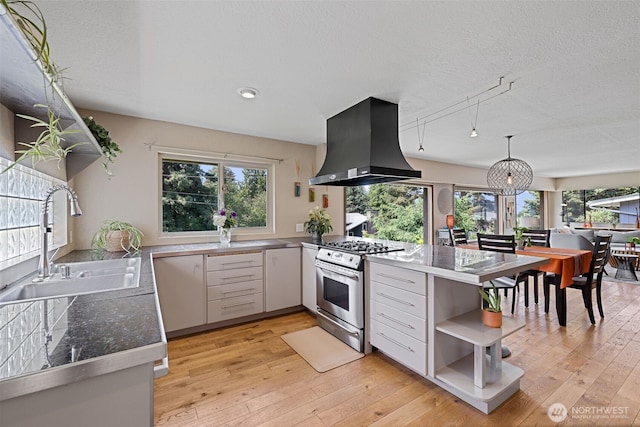 8814 Earl Ave NW, Seattle, WA 98117 - kitchen featuring stainless steel gas range oven, island range hood, open shelves, light wood finished floors, and a textured ceiling
