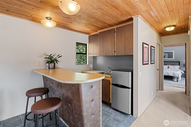8814 Earl Ave NW, Seattle, WA 98117 - kitchen with freestanding refrigerator, wooden ceiling, a breakfast bar, a peninsula, and light countertops