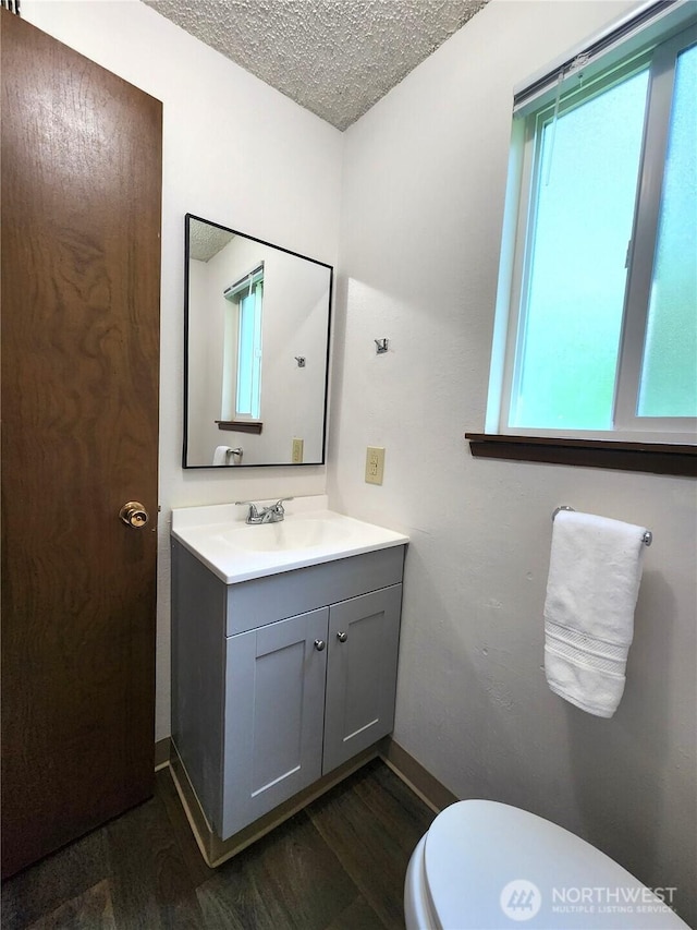 4608 73rd Street Ct E, Tacoma, WA 98443 - bathroom featuring vanity, wood finished floors, a textured ceiling, toilet, and baseboards