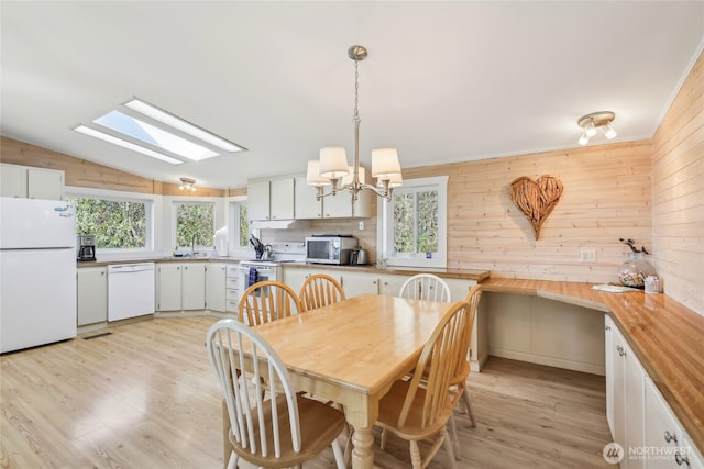 3486 Holmes View Dr, Langley, WA 98260 - dining room featuring plenty of natural light, light wood finished floors, a skylight, a chandelier, and vaulted ceiling